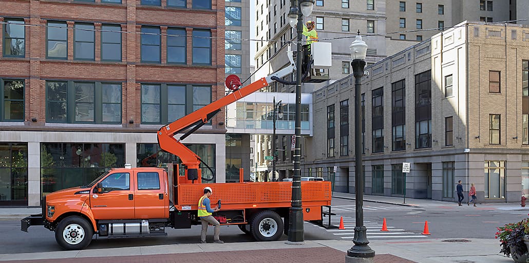 Ford Medium Duty with a cherry picker lifting an electrical worker to repair a street light.