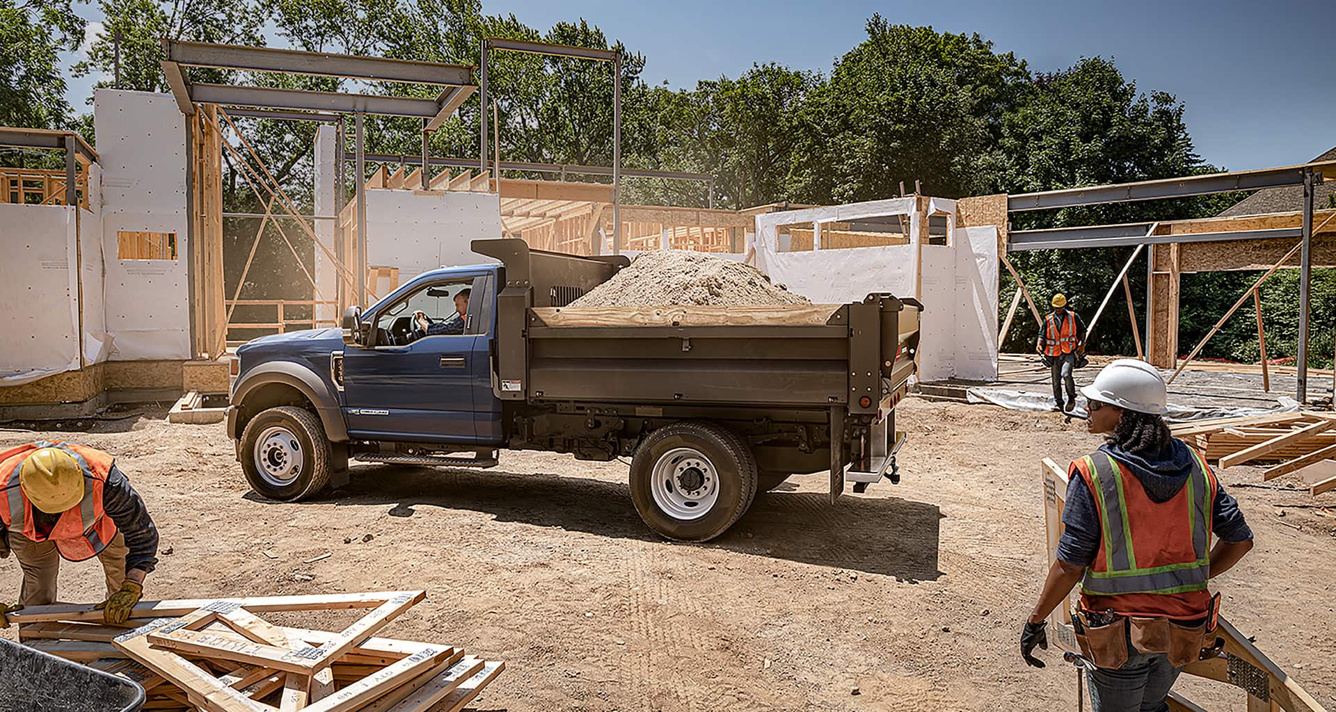 A 2020 Ford Super Duty chassis dump truck is being filled with dirt at a construction site.