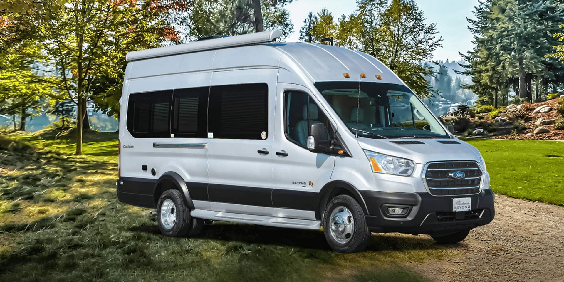 A silver Transit is parked on a dirt road.