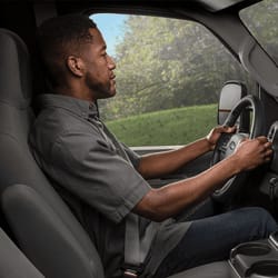 Profile image of a man driving with both hands on the wheel.